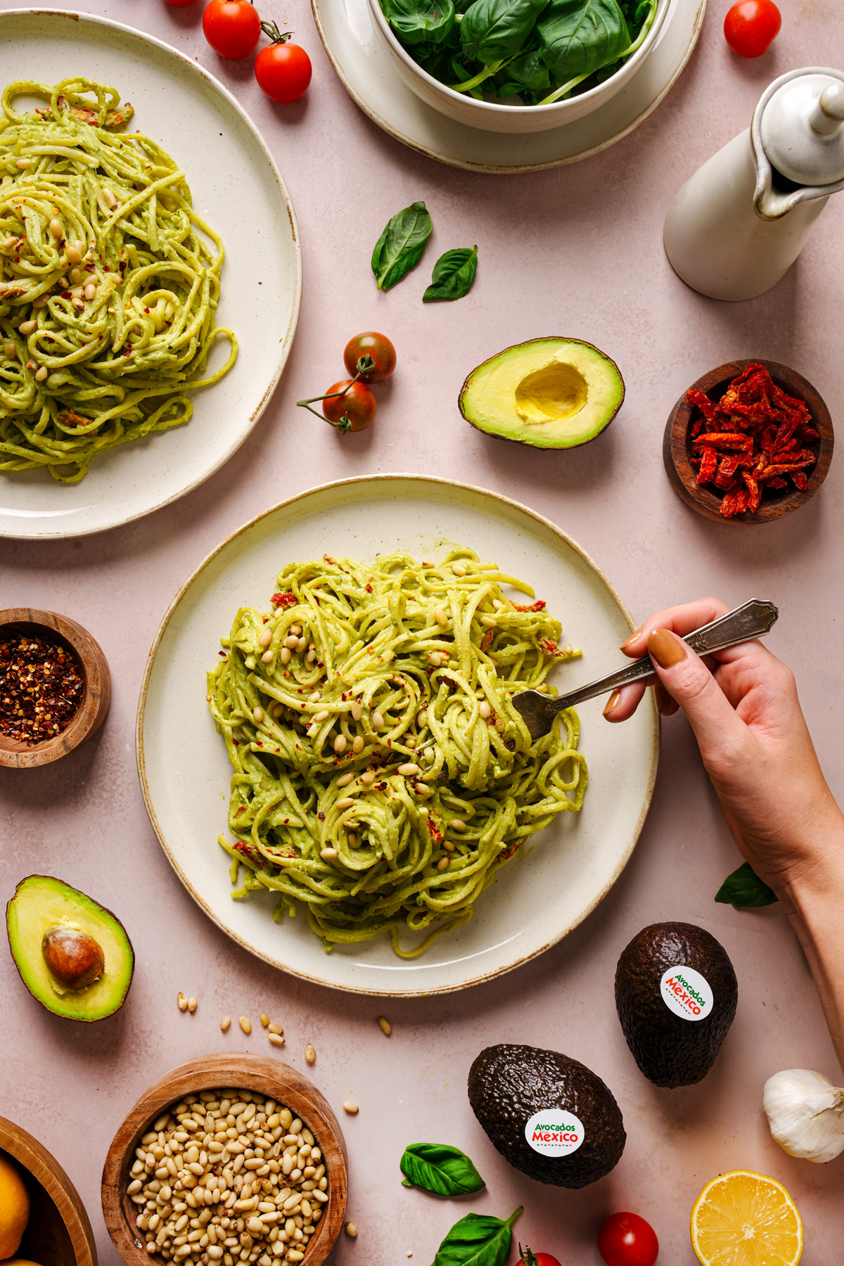 a hand swirling the avocado pesto pasta around with a fork