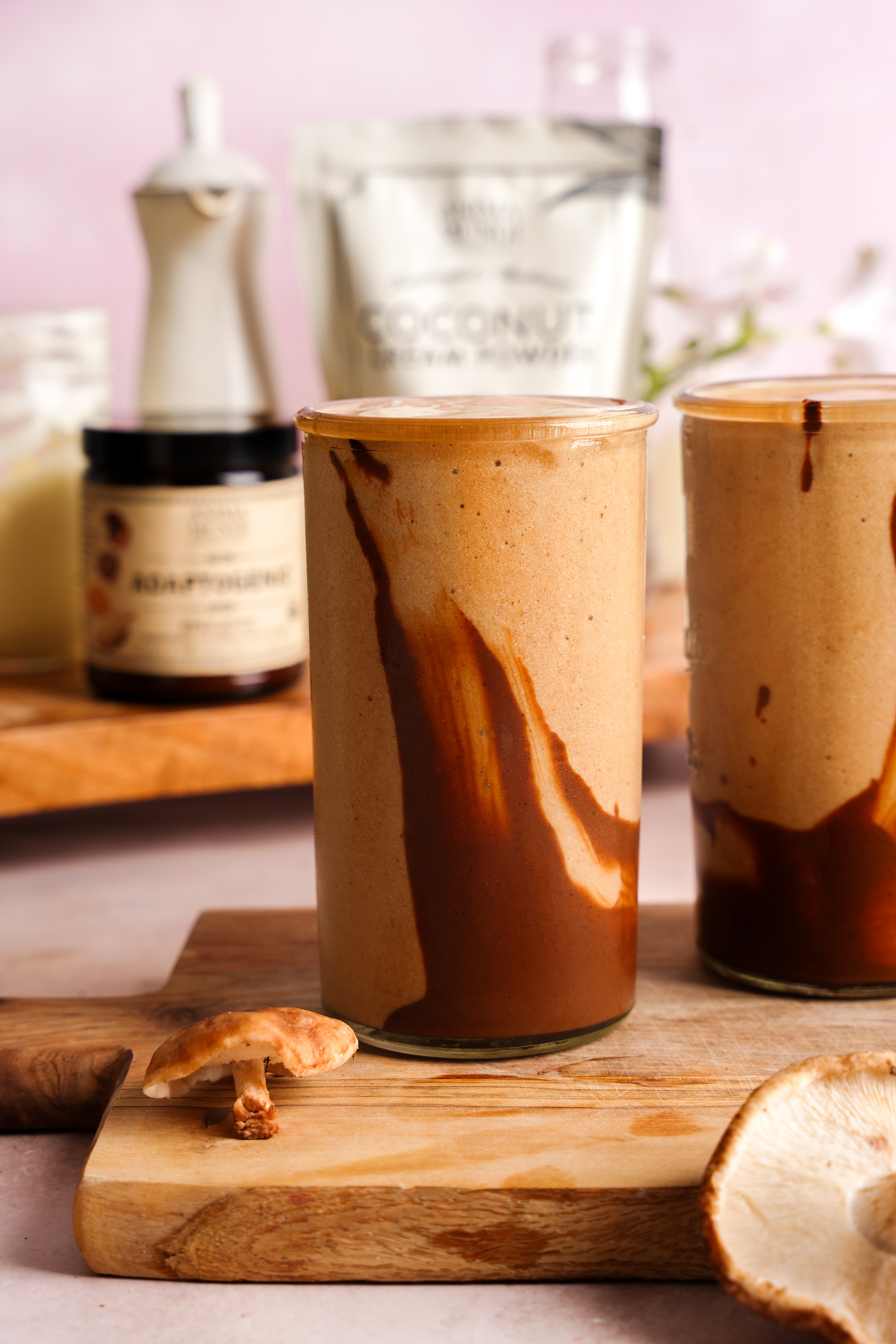 the mushroom smoothie in glasses with the anima mundi products behind it