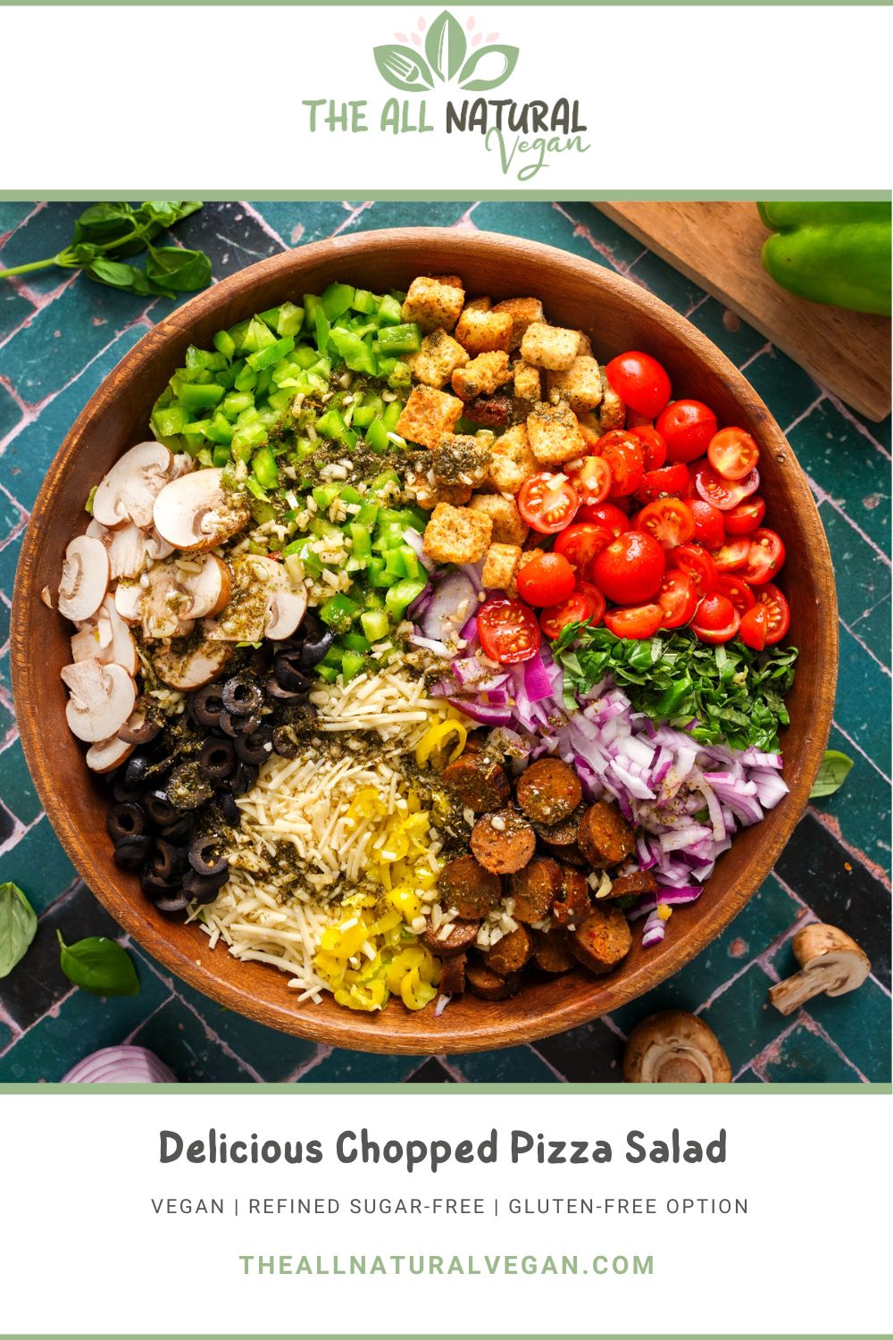 Colorful vegan chopped pizza salad in a wooden bowl with fresh toppings like cherry tomatoes, vegan sausage, olives, mushrooms, green bell peppers, red onions, vegan cheese, banana peppers, basil, and croutons. Branded with The All Natural Vegan logo and recipe title
