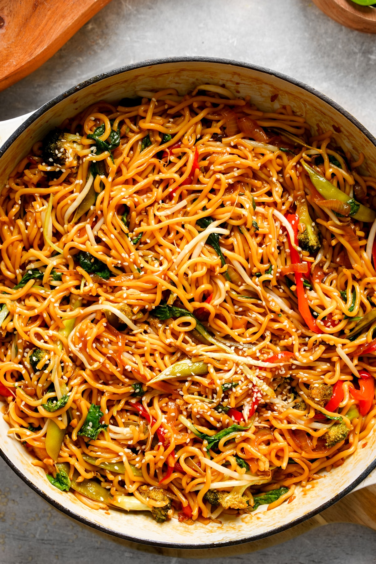 A pot filled with healthy vegan chow mein noodles mixed with colorful vegetables such as bok choy, red bell pepper, and broccoli. The noodles are coated in a glossy soy-based sauce and sprinkled with sesame seeds, creating a vibrant, flavorful plant-based stir-fry.